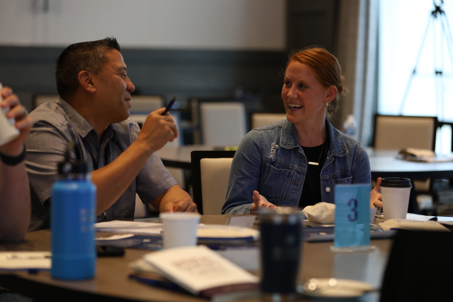 Two owners laughing at a round table during a workshop