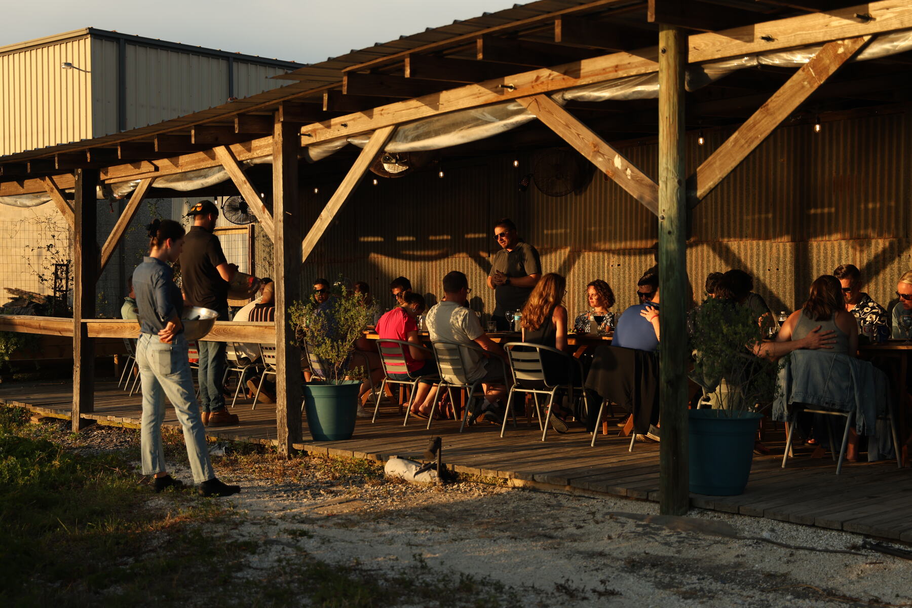 Retreat guests at dinner under a wooden pavilion at sunset